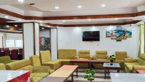 A hotel lobby with yellow armchairs, a TV mounted on the wall, and a wooden ceiling. - Charming Durbar Hotel  (Kathmandu)