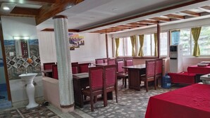 A restaurant with wooden ceiling beams, tiled floor, and red upholstered chairs. - Charming Durbar Hotel  (Kathmandu)