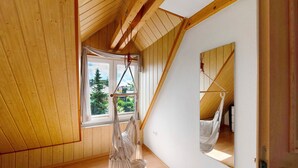 Une pièce avec des lambris en bois, une grande fenêtre et un hamac.