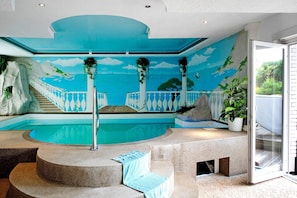 Une piscine ornée d’une fresque murale, des marches menant à la piscine et une plante en pot.