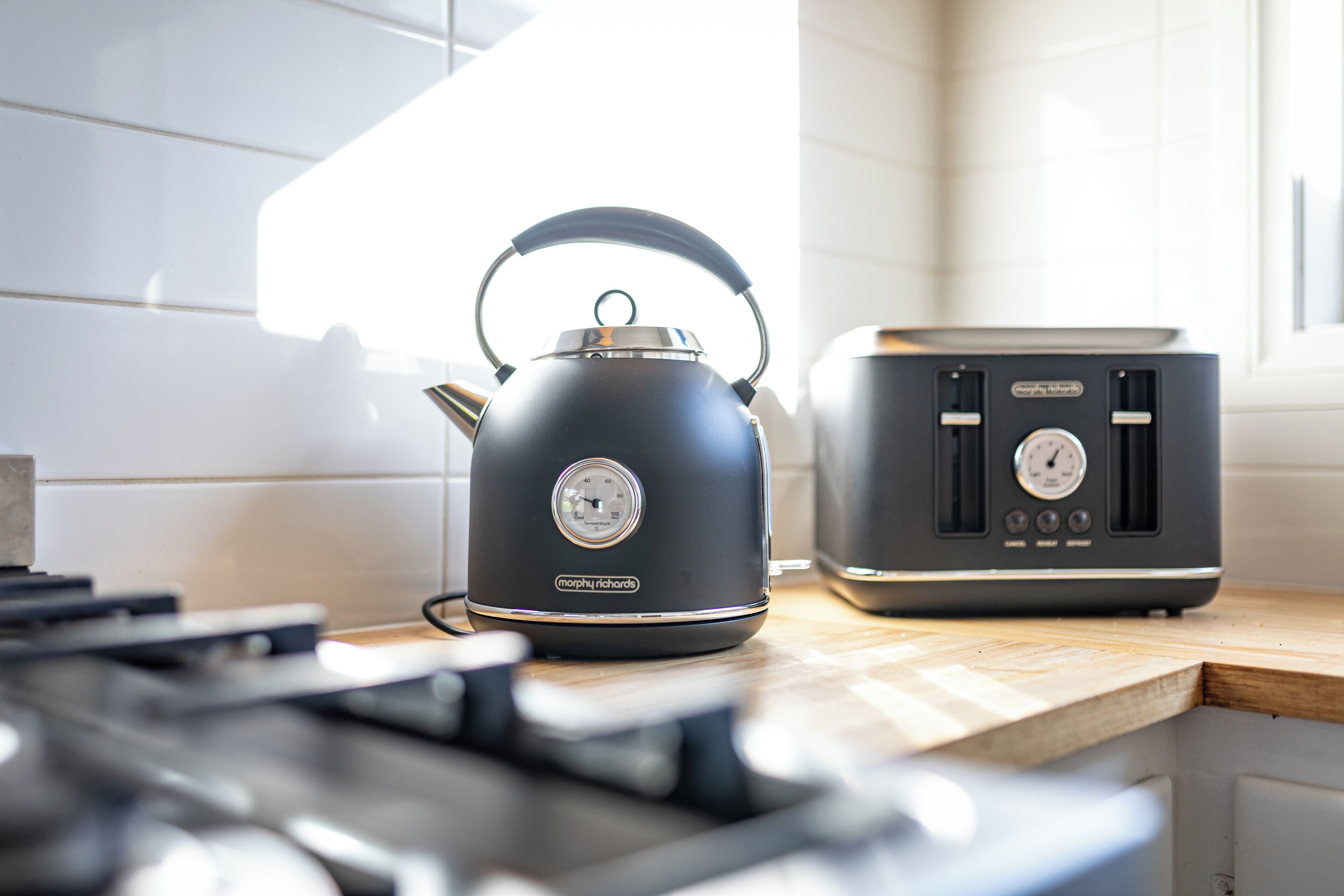 Eine Küche mit einem schwarzen Wasserkocher und einem Toaster auf einer Holzausziehtischplatte.