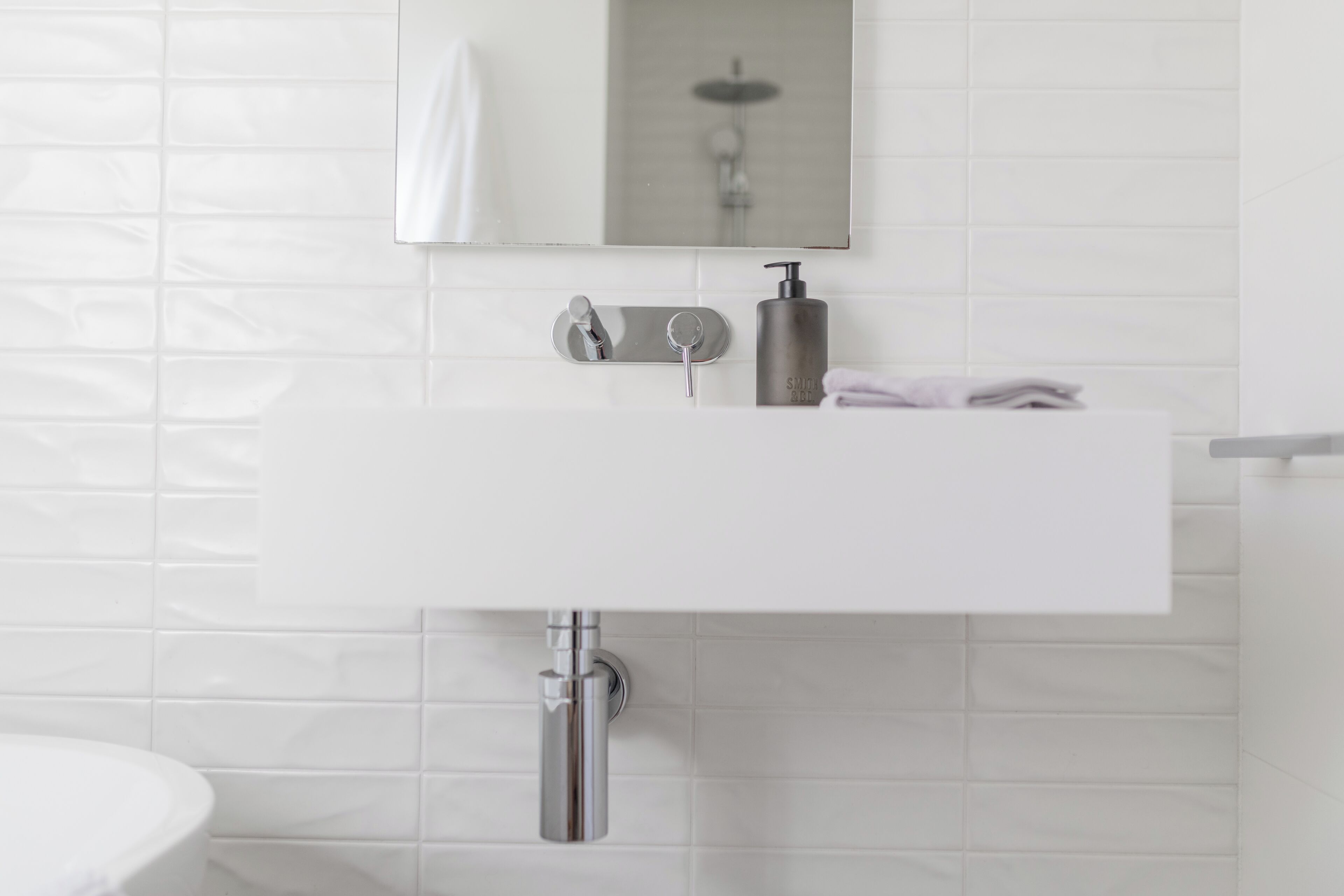 A bathroom with a white sink, a mirror, and a towel rack.