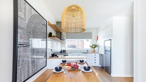 Une cuisine moderne avec une table à manger en bois pour quatre personnes, un luminaire suspendu et un grand élément décoratif mural.