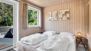 A bedroom with a large bed, a window with curtains, and a view of the outdoors. - "Rohan" - 700m from the sea by Interhome (Rødby)