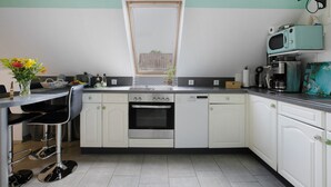 A kitchen with white cabinets, a stainless steel oven, a microwave, and a window with a view of a building. - Apartment 'De Lütte Moehl' with Natural Swimming Pond and Shared Terrace (Hollingstedt)