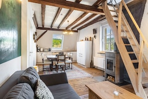 A cozy interior with a wooden ceiling, a dining area, a kitchen, and a fireplace.