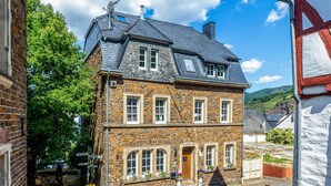 A two-story stone building with a gabled roof, a central entrance, and a small front garden. - Spacious Holiday Apartment with Fireplace in Winzerhaus Schenk, with Mountain View and Wi-Fi (Neef)