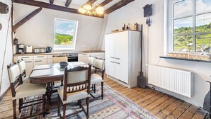 A kitchen with wooden beams, a dining table with chairs, a window with a view, and a white refrigerator. - Spacious Holiday Apartment with Fireplace in Winzerhaus Schenk, with Mountain View and Wi-Fi (Neef)