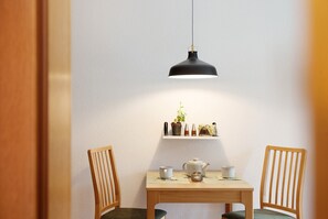 A dining area with a table, chairs, a hanging light fixture, and a shelf with decorative items. - Apartment 'Ferienwohnung Reschbergwies'n' with Mountain View, Balcony and Wi-Fi (Farchant)