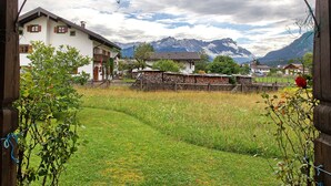 A rural setting with a house, a wooden fence, and mountains in the background.
