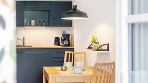 A modern kitchen with dark cabinets, a wooden dining table, and a hanging pendant light.