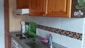Une cuisine avec des meubles en bois, une cuisinière, un appareil électroménager vert et une décoration sur le thème du café.