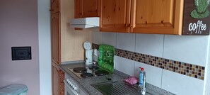 Eine Küche mit Holzausstattung, einem Herd, einem grünen Gerät und einer Kaffeedeko.