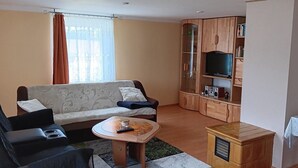 Un salon comprenant un canapé, une table basse, un téléviseur et un meuble.