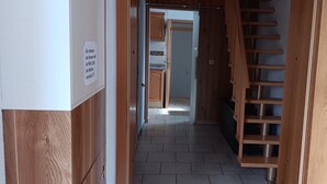 Un couloir avec une porte en bois, un sol carrelé et un panneau sur le mur.