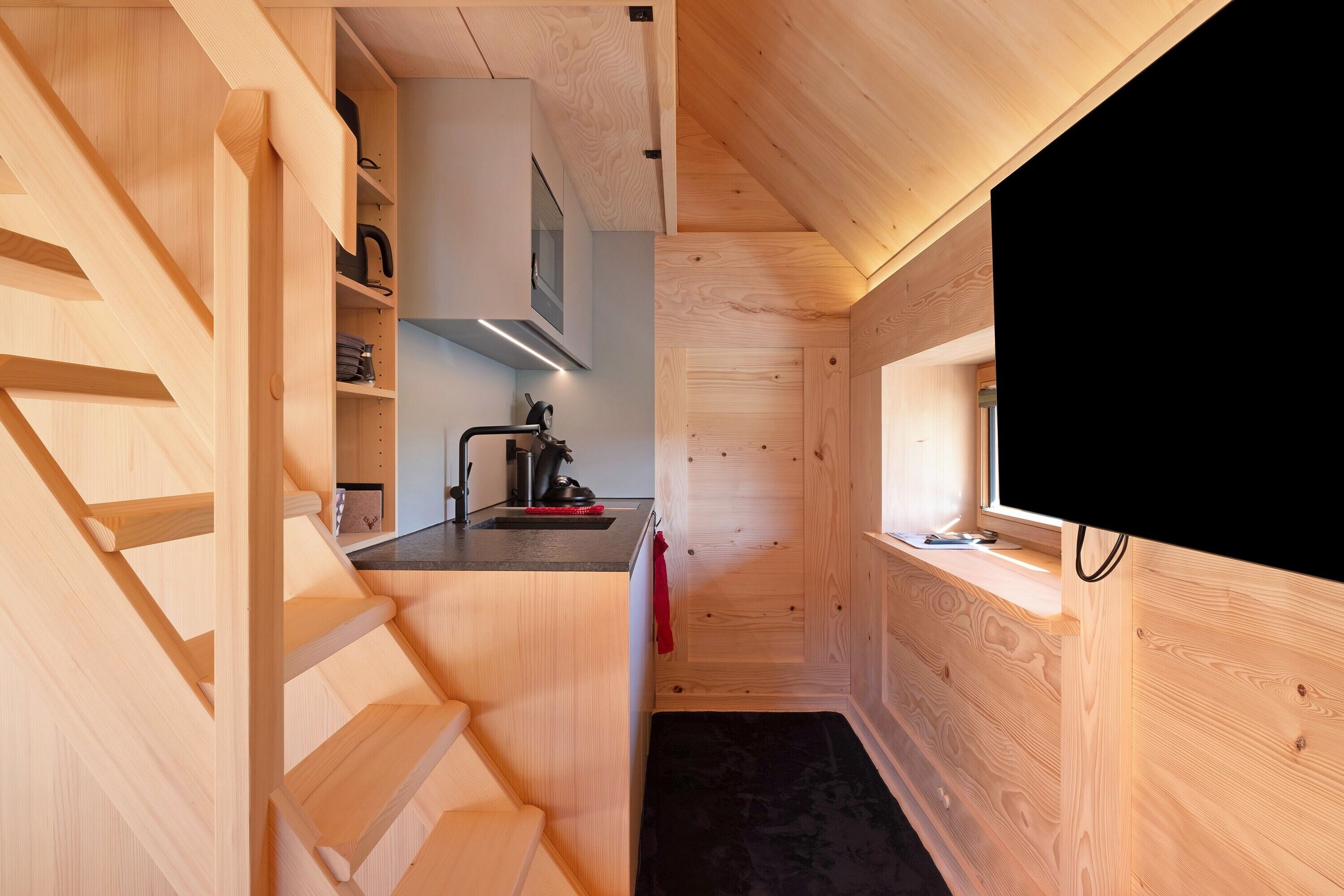 A compact kitchen with wooden cabinetry, a built-in stove, and a window.