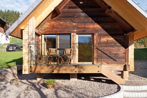 Eine Holzhütte mit einem Balkon, einem Tisch mit Stühlen und einem kleinen Garten.