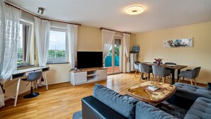 Un salon comprenant un canapé, un téléviseur, une table à manger et des chaises.