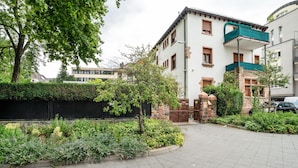 Un immeuble résidentiel doté d’un balcon, d’une allée pavée et d’un espace jardin.