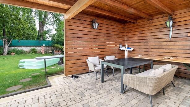 Une terrasse extérieure dotée d’un plafond en bois, d’une table, de chaises et d’un petit bateau.