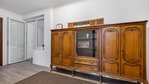 A wooden cabinet with glass doors, a clock, and a radio on top. - Apartment 'Ferienwohnung Am Theaterplatz' with Wi-Fi (Gera)