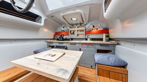 Een kleine keuken met een houten tafel, een bankje en een zithoekje.