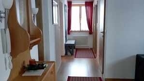 Un couloir avec un banc en bois, un radiateur et un tapis rouge.