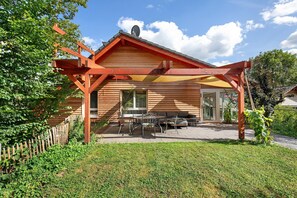 Ein Holzhaus mit einer Terrasse, einem Tisch und Stühlen.
