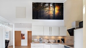 A modern kitchen with white cabinets, a built-in oven, and a coffee maker. - Holiday Apartment "Leben Am Weinberg" with Shared Terrace, Shared Garden & Wi-Fi (Herbstein)