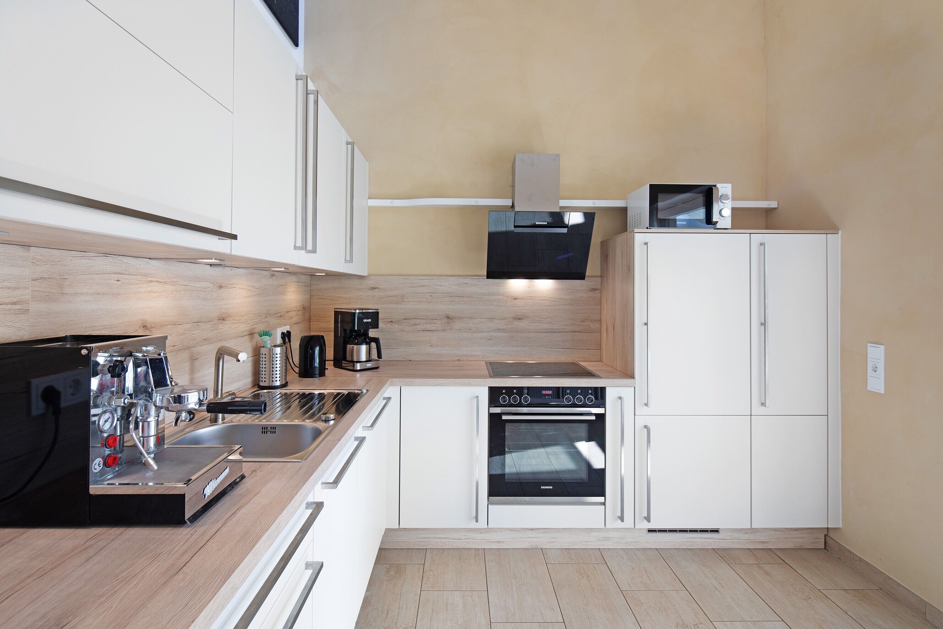 Eine moderne Küche mit eingebautem Backofen, Mikrowelle und Kaffeemaschine.
