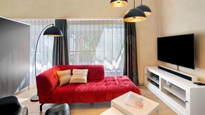 A modern living room with a red sofa, a flat-screen TV, and pendant lights. - Holiday Apartment "Leben Am Weinberg" with Shared Terrace, Shared Garden & Wi-Fi (Herbstein)