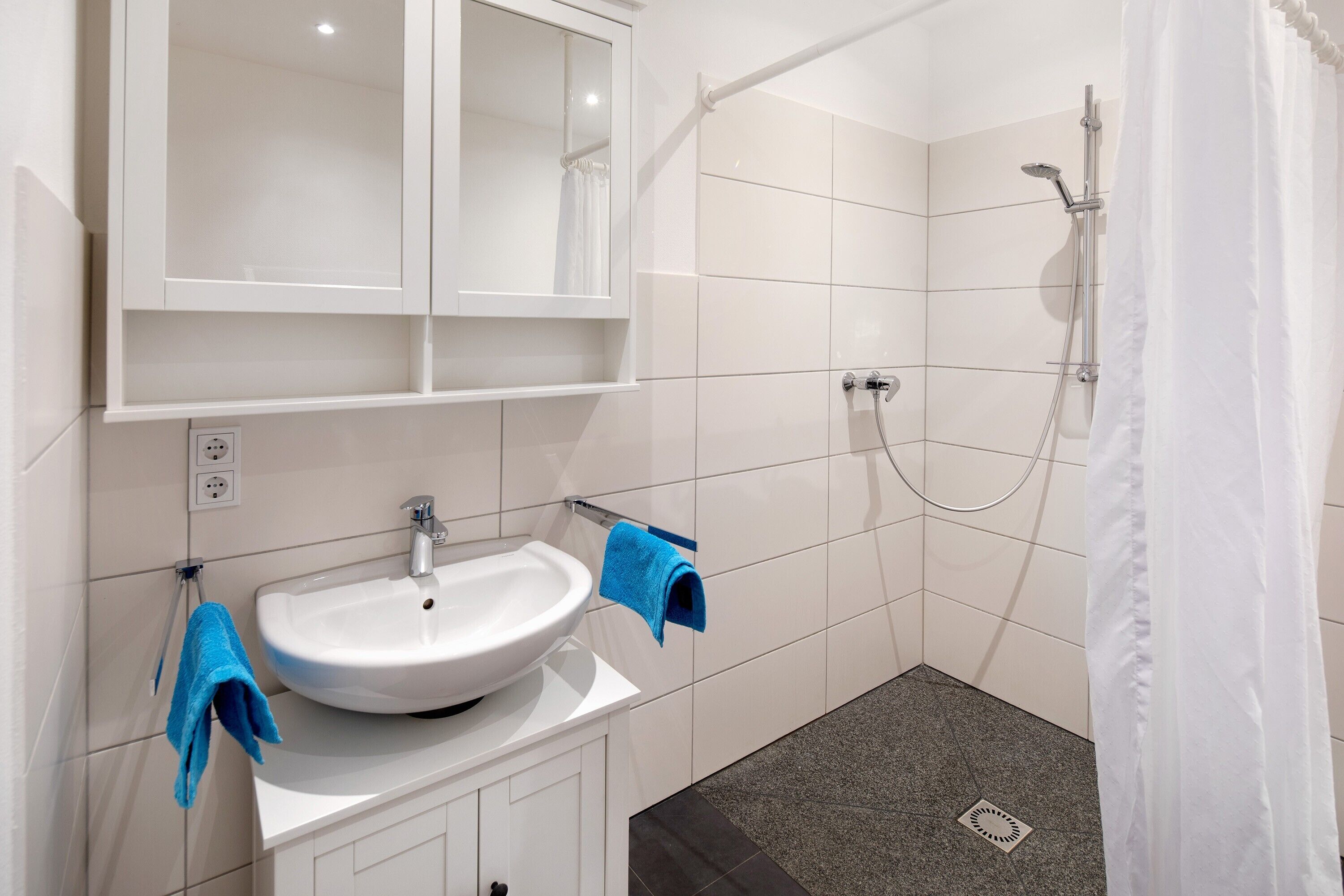 Ein Badezimmer mit Waschbecken, Spiegel und Dusche.
