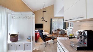 A modern kitchen with a coffee machine, a dining area with a table and chairs, and a seating area with a sofa and a TV. - Holiday Apartment "Leben Am Weinberg" with Shared Terrace, Shared Garden & Wi-Fi (Herbstein)