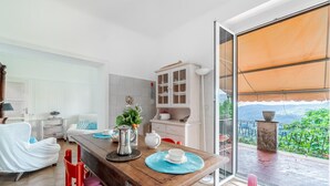 Comedor con mesa de madera, sillas y vista a la vegetación a través de un ventanal.