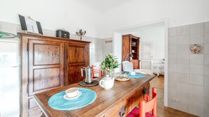 Un comedor con una mesa de madera, sillas y una cocina al fondo.