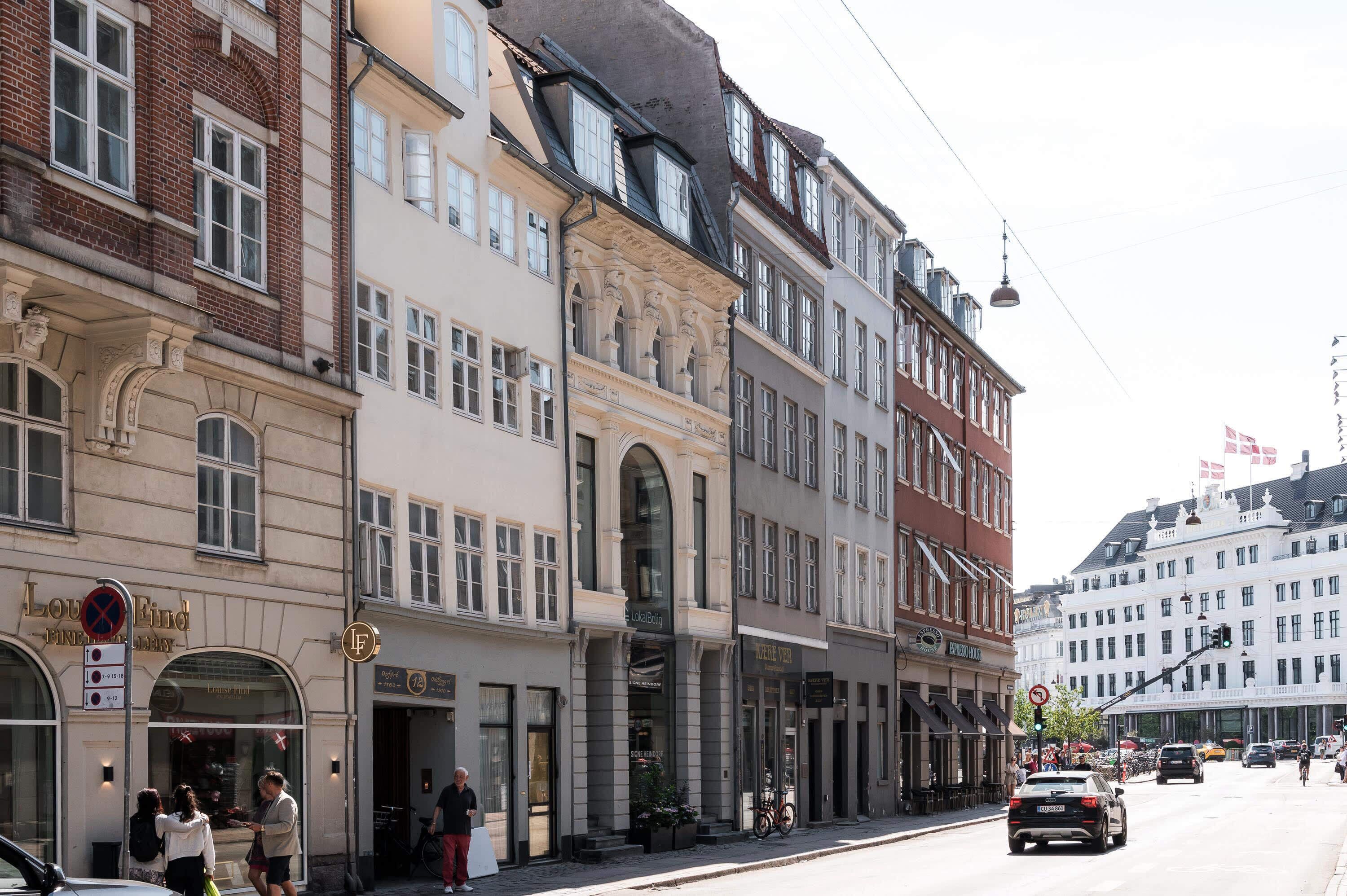 En gatubild från en europeisk stad med historiska byggnader, ett kafé och en cykel som står parkerad utanför.