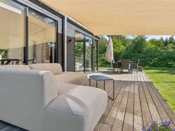 Un patio moderno al aire libre con un sofá, una mesa pequeña y una silla.