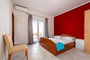 Een slaapkamer met een bed, een stoel, een kledingkast, een nachtkastje en een airconditioning.