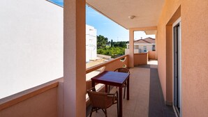 A balcony with a table and chairs, a view of the city, and a building in the background.