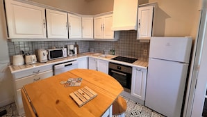 A compact kitchen with white cabinets, a microwave, a coffee maker, and a refrigerator.