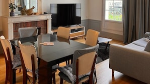 A modern living room with a dining table, chairs, a sofa, a TV, and a decorative globe light.