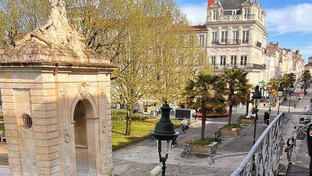 A stone archway, a paved pathway, and a wooden table with a bowl and glasses.