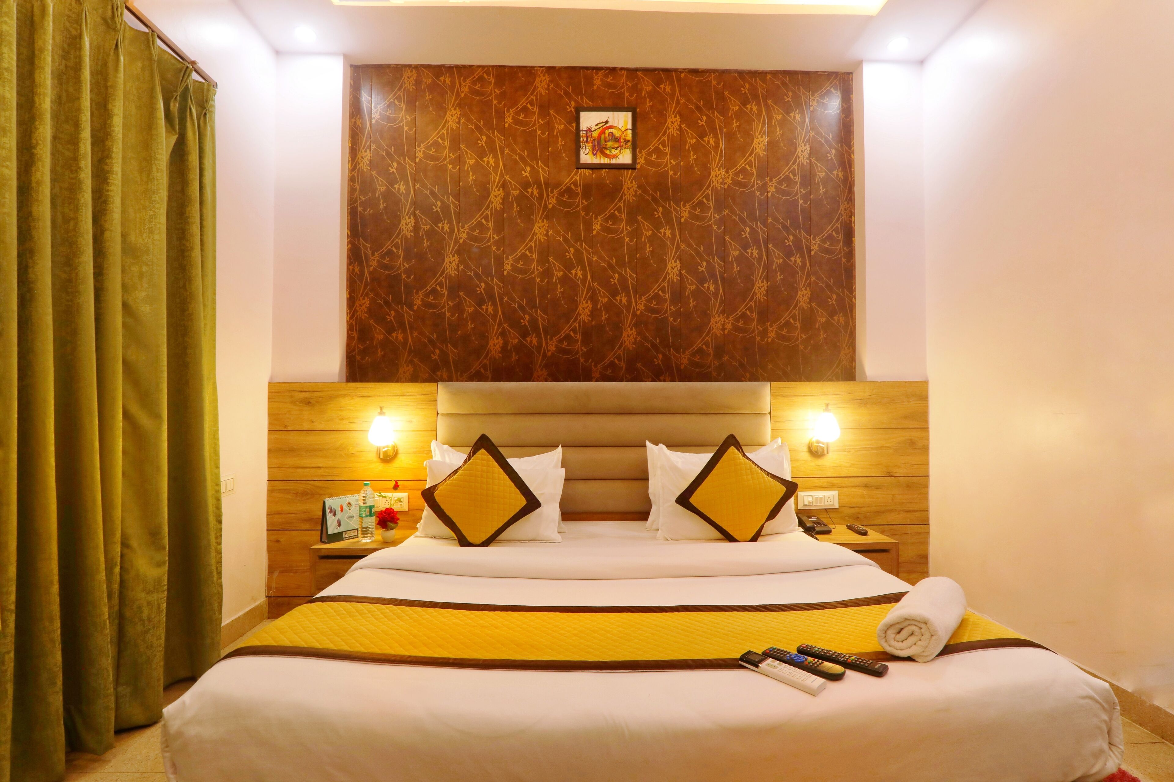 A hotel room with a large bed, wooden headboard, and a wall-mounted artwork.