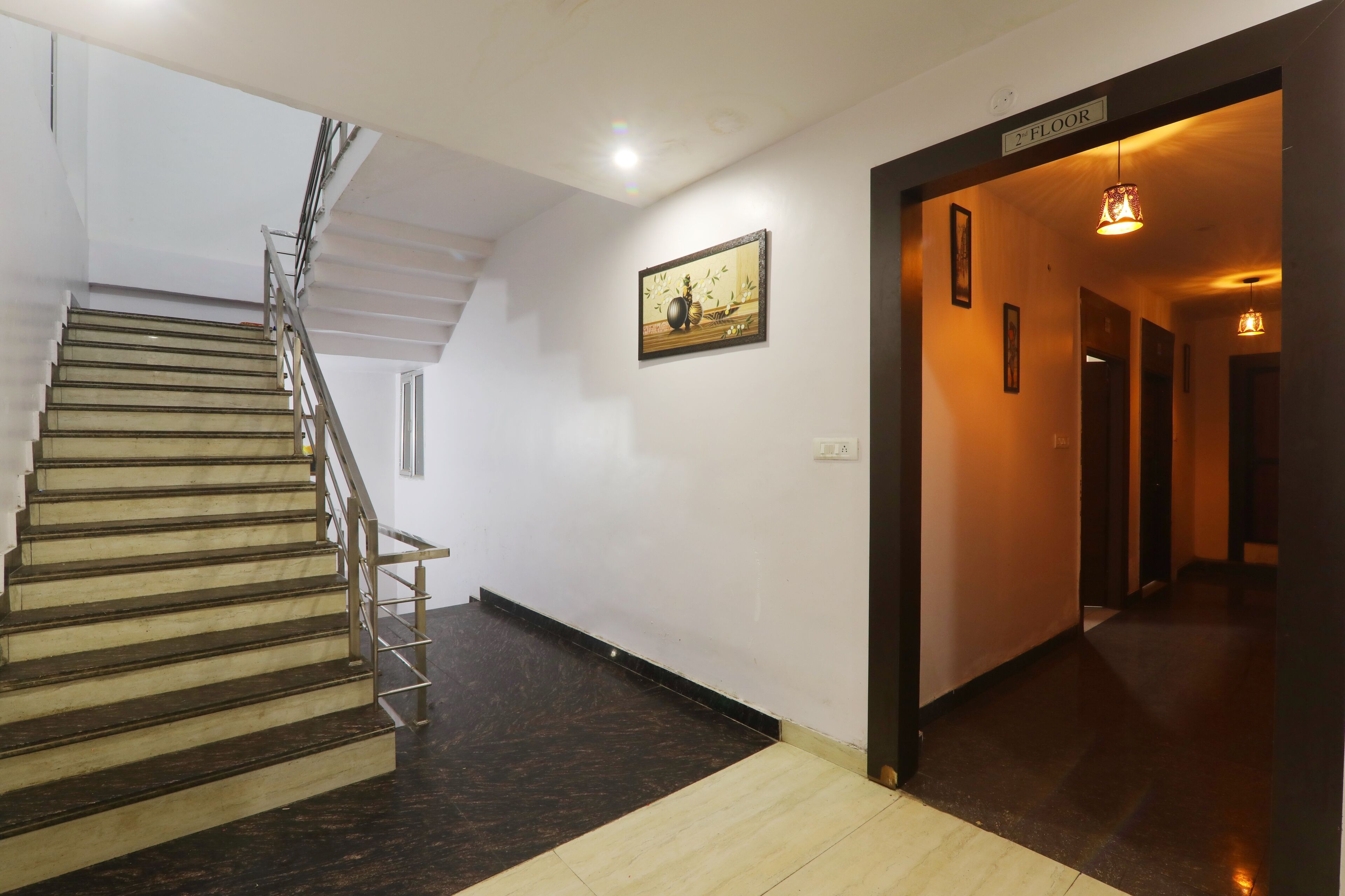 A staircase with a handrail, a wall-mounted picture, and a sign indicating the second floor.