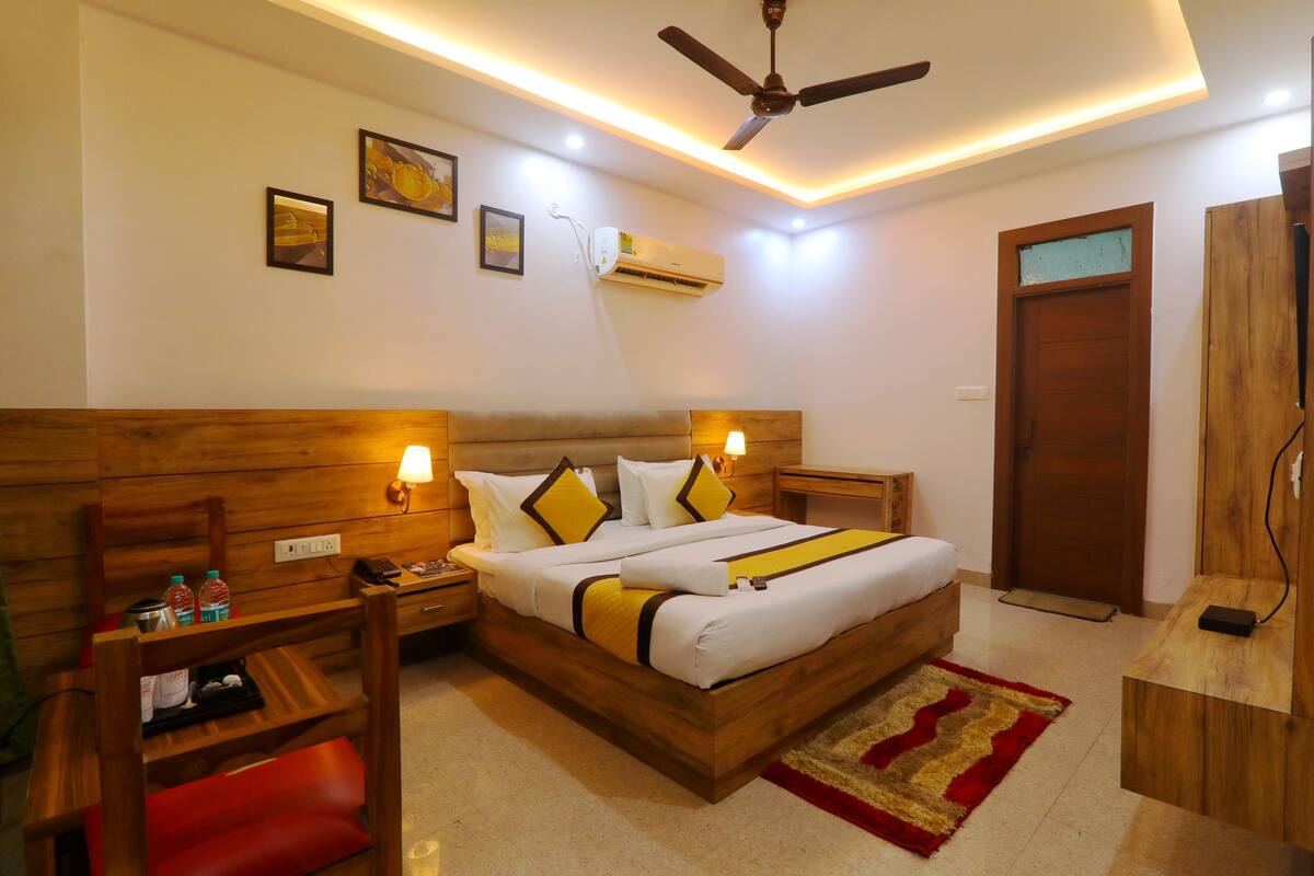 A hotel room with a wooden bed, bedside tables, a desk, a chair, and a ceiling fan.