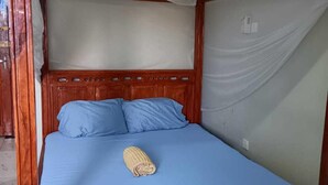A four-poster bed with a canopy, blue bedding, and a rolled towel on the bed. - Lux Suites Vee Studio Apartments Bamburi (Mombasa)