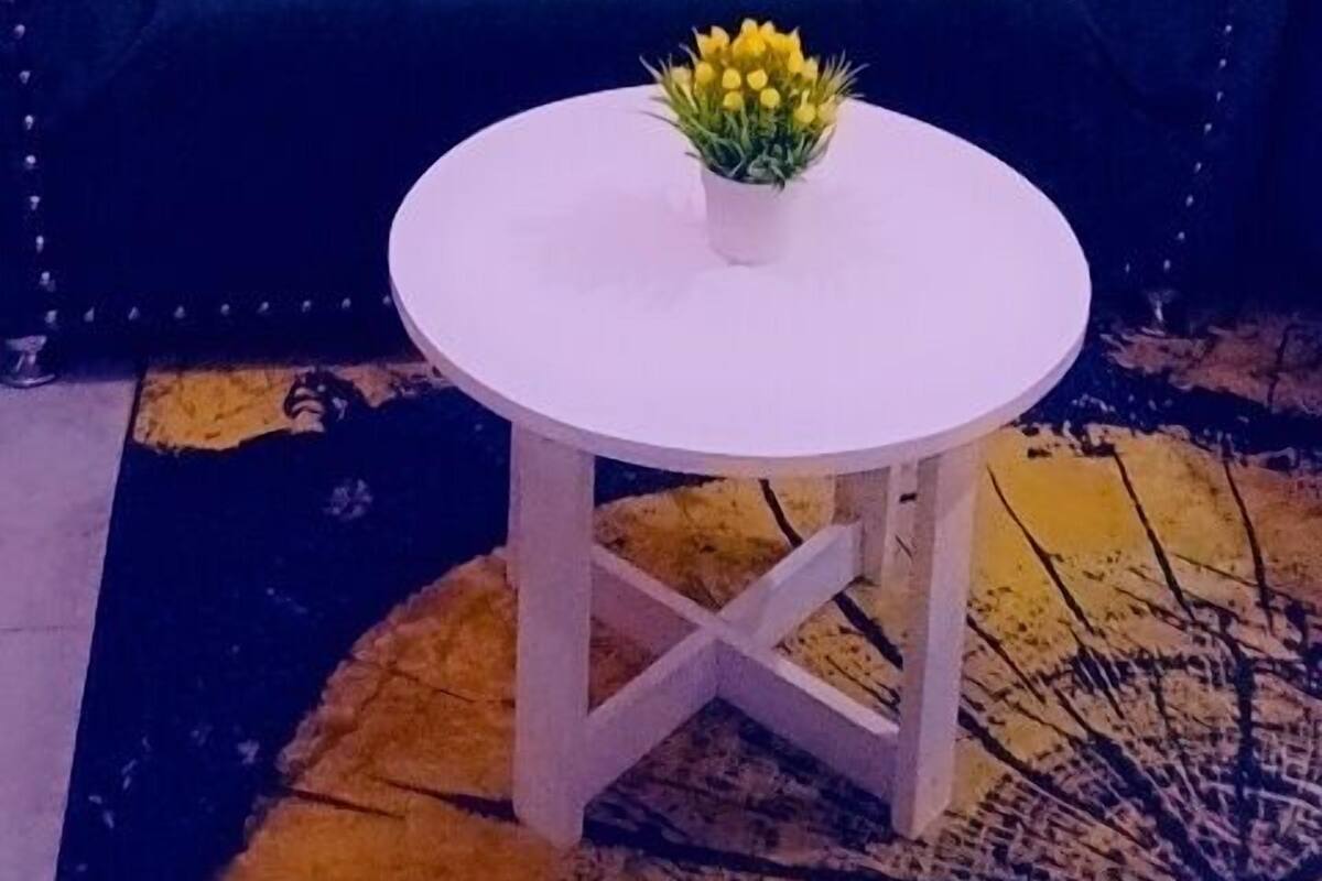 A room with a dark blue sofa, a white round table with a yellow flower centerpiece, and two circular wall decorations.