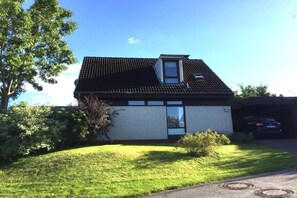 Une maison de plain-pied avec un toit en pente, une petite fenêtre de grenier et une porte de garage.