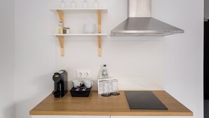 Una cucina con una moka, tazze, una bottiglia d'acqua e un tappetino di benvenuto.