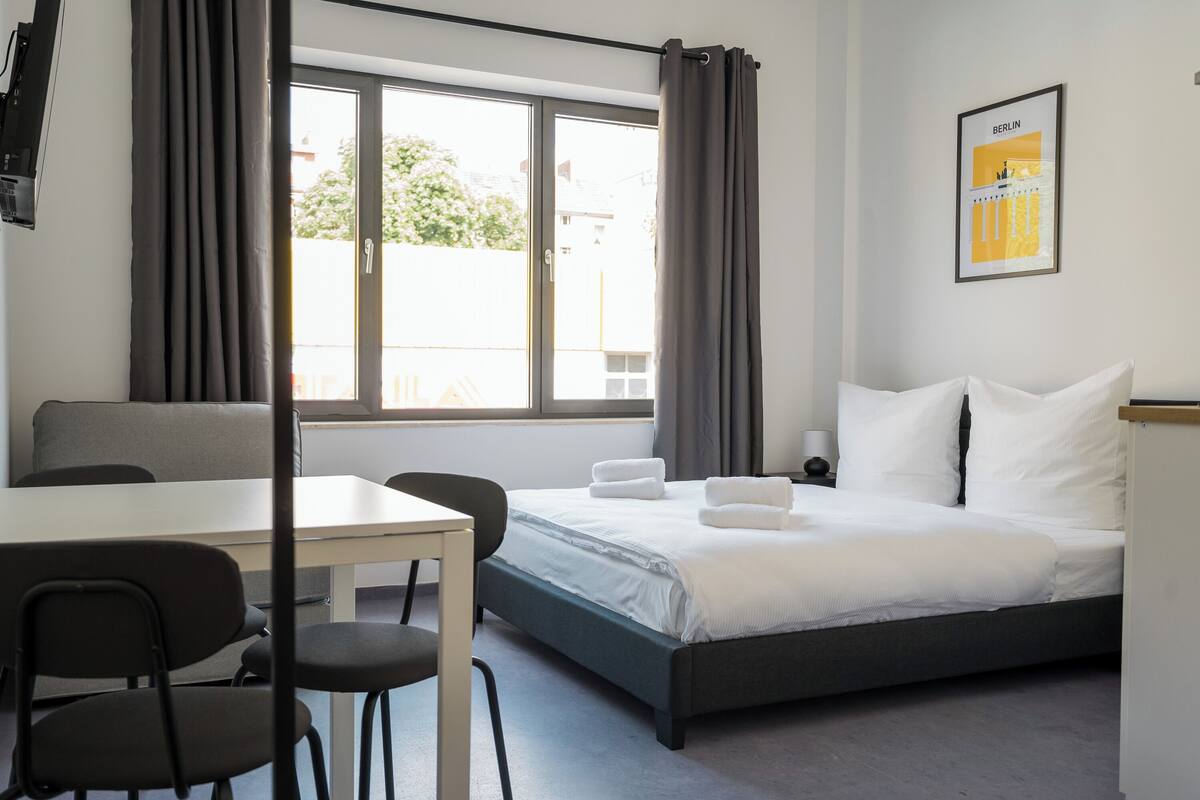 A hotel room with a bed, a table, and chairs.